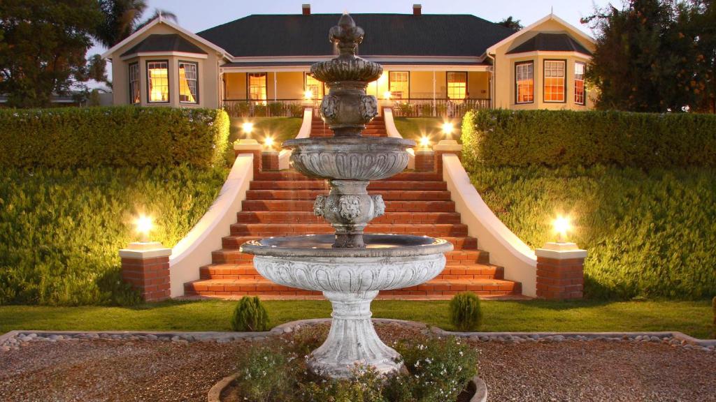 a fountain in front of a house with lights at La Plume Boutique Hotel & Spa in Oudtshoorn