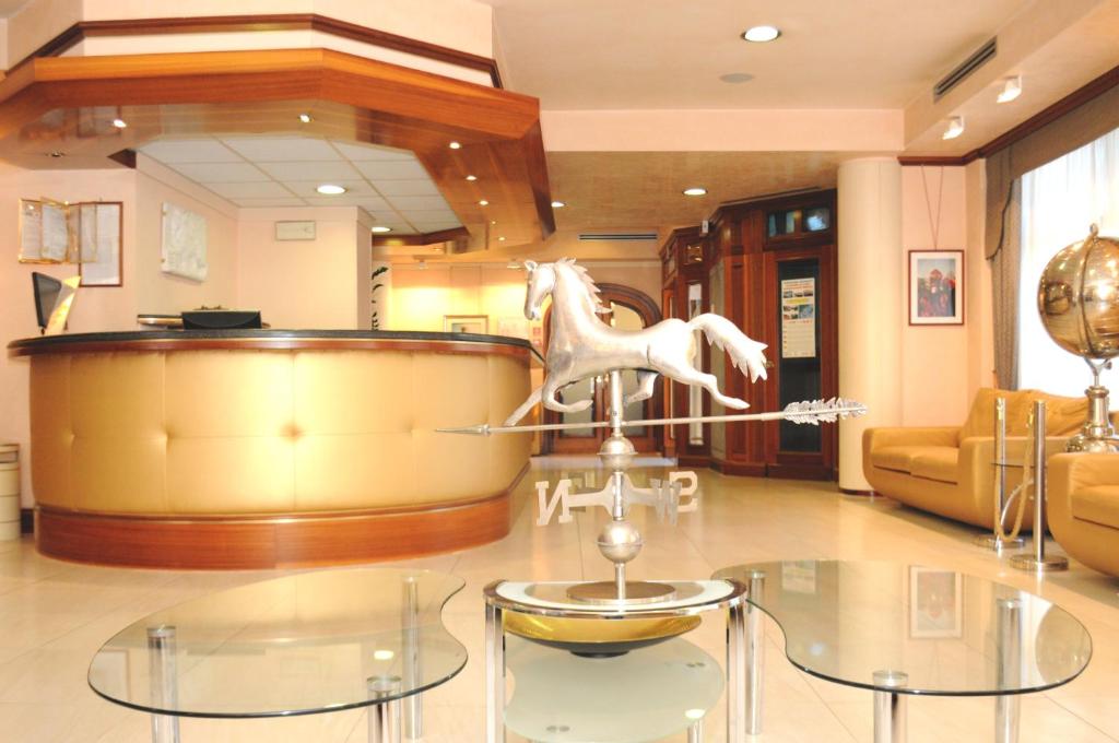 マルゲーラにあるホテル モンディアルの白馬の置かれたガラスのテーブルが備わるお部屋