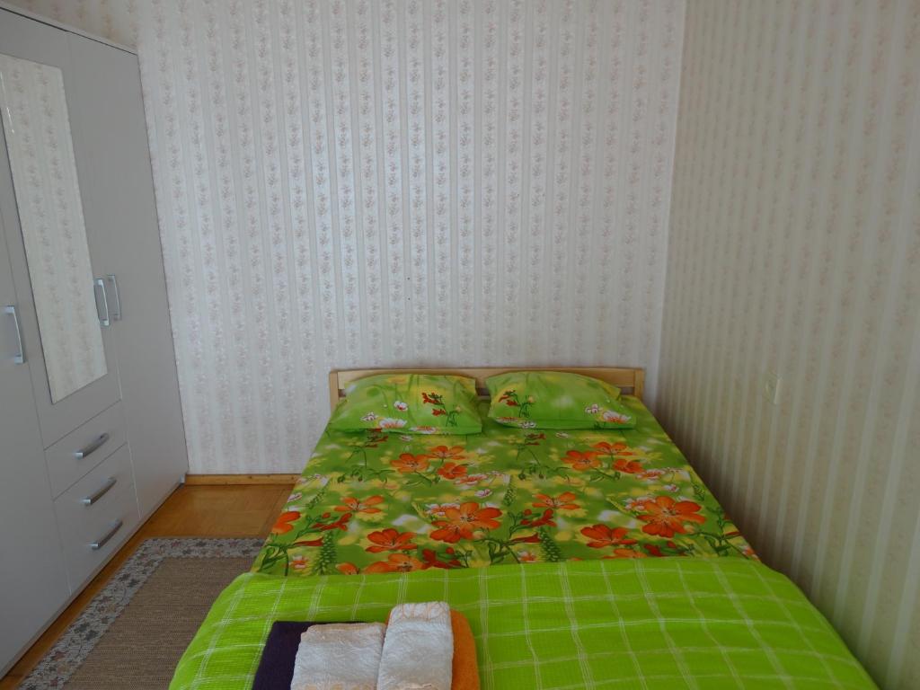 Dormitorio pequeño con cama con edredón verde en Frendlen Papiniidu Apartment, en Pärnu
