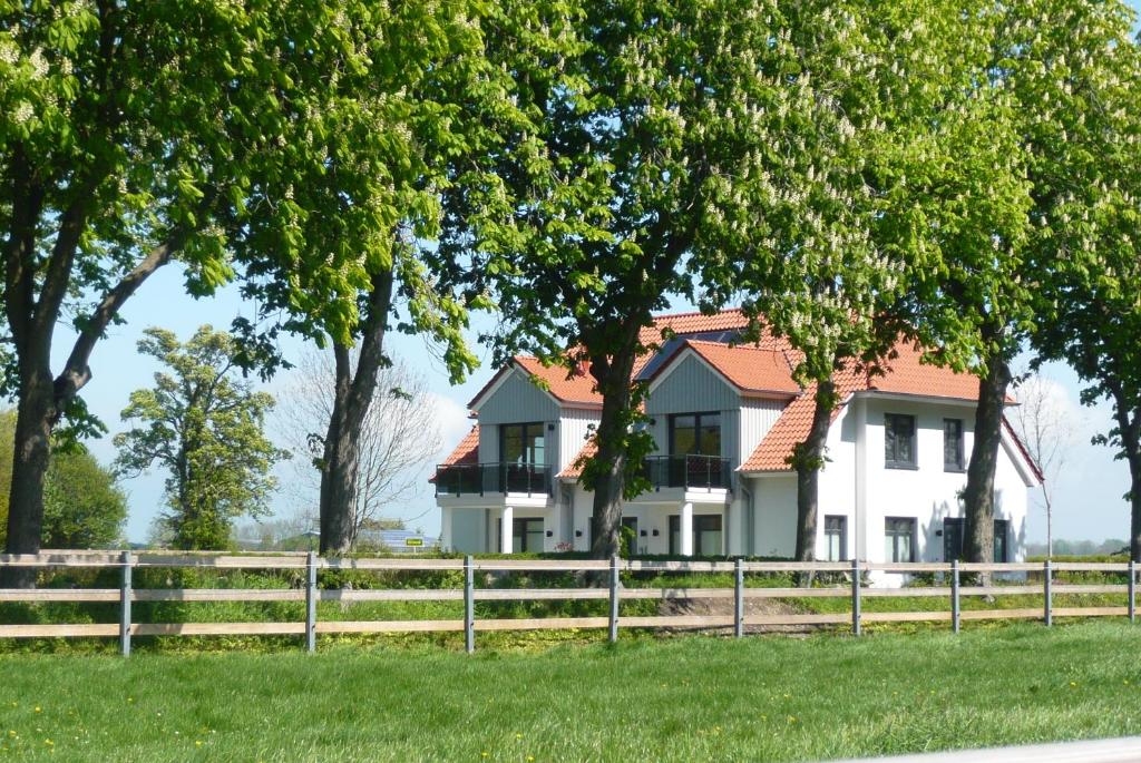 a white house with a fence and trees at Ferienhaus Bellevue in Fehmarn