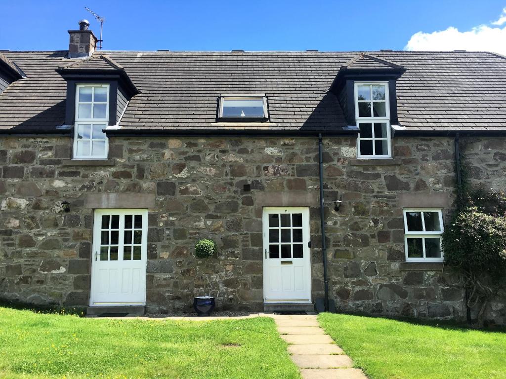 an old stone house with two white doors at Dunnottar Woods House in Stonehaven