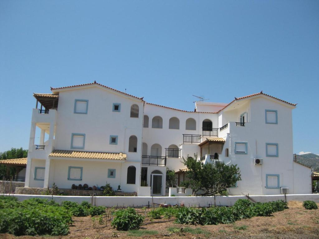 Un grand bâtiment blanc avec de nombreuses fenêtres dans l'établissement Maravelias House, à Archangelos