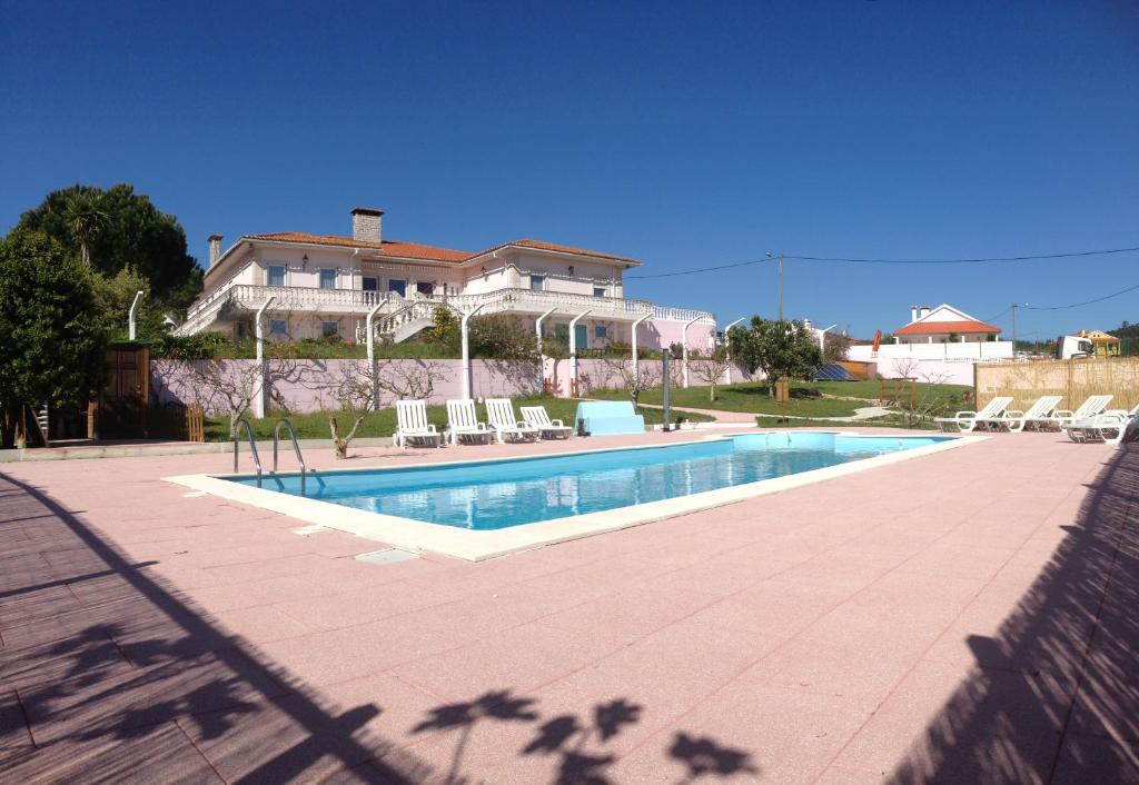 a swimming pool in front of a house at Domestival in Vila Verde dos Francos