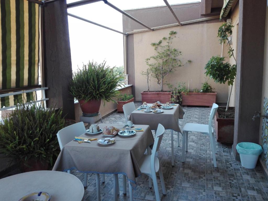 パレルモにあるB&B Pisaniのパティオ(テーブル2台、白い椅子、植物付)