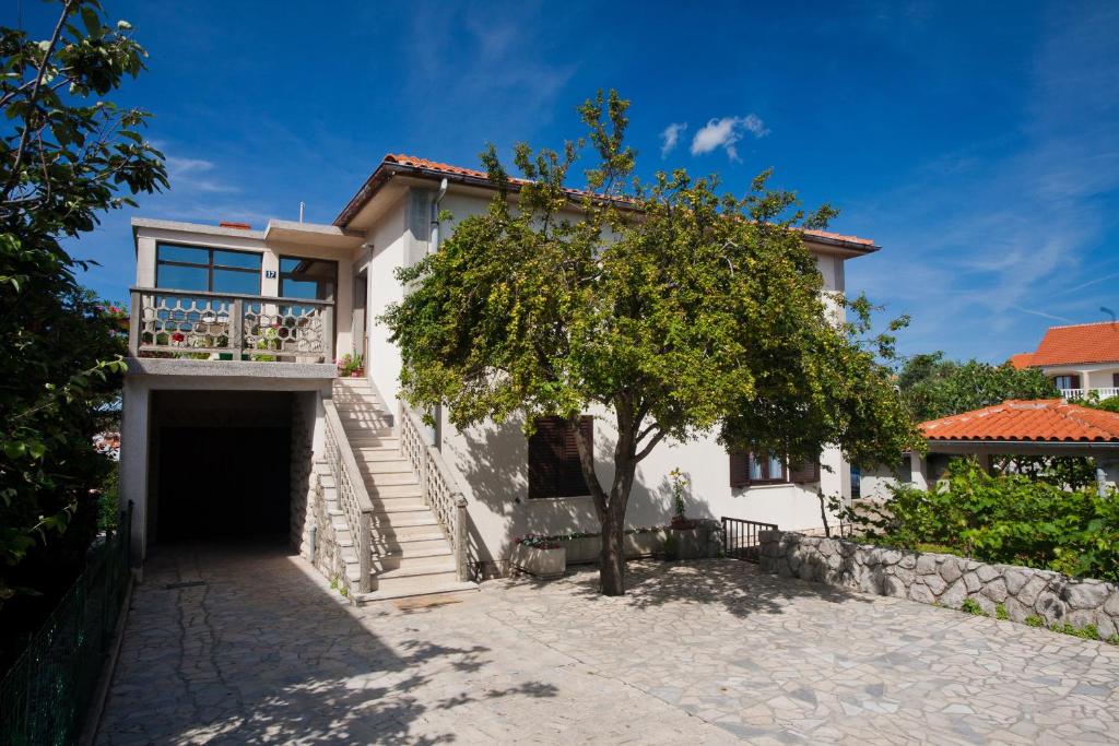 une maison blanche avec des escaliers et un arbre dans l'établissement Apartment Milka, à Krk