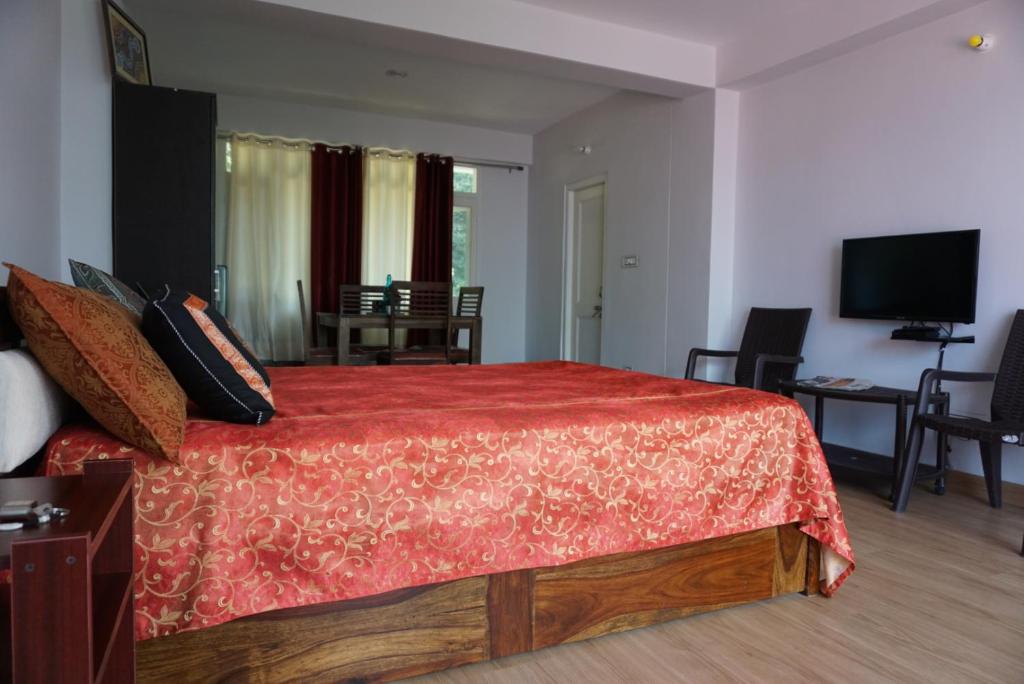 Un dormitorio con una cama grande con una colcha roja. en Satobari Greens Homestay, en McLeod Ganj