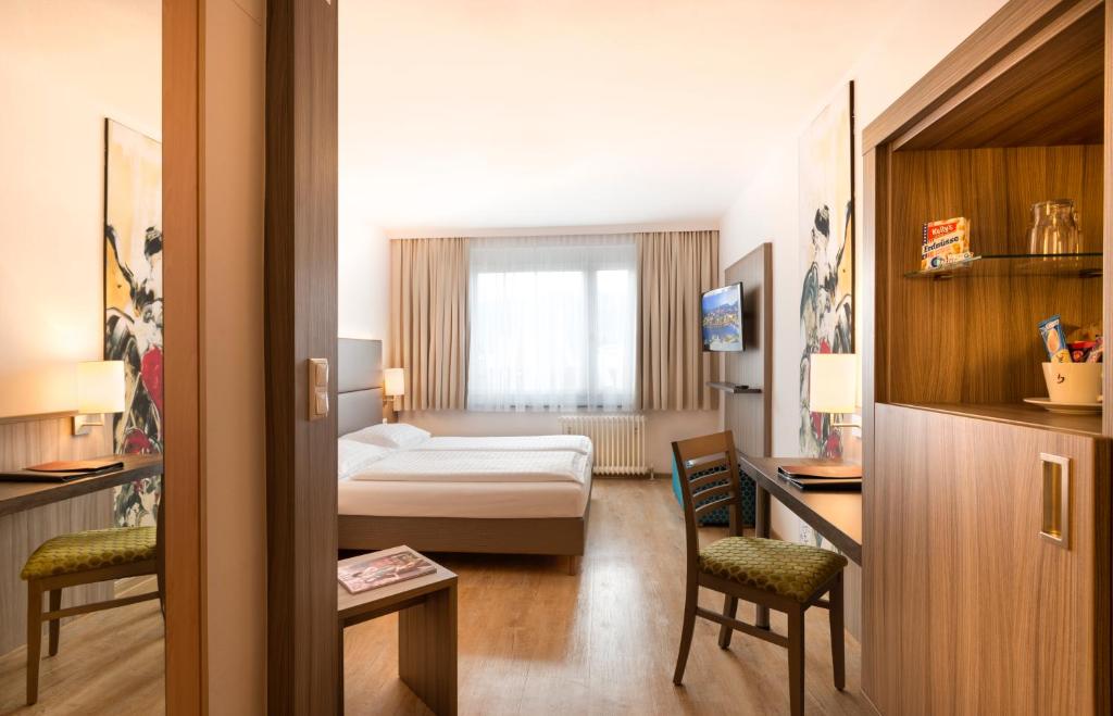 a hotel room with a bed and a desk and chairs at Hotel City in Villach