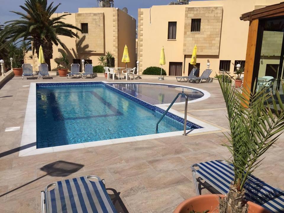 einen Pool im Innenhof mit Stühlen und einem Gebäude in der Unterkunft Dimma Seaside Houses in Paphos City