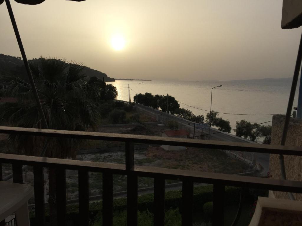 a view of the ocean at sunset from a balcony at Vlastos Apartment in Kalamos