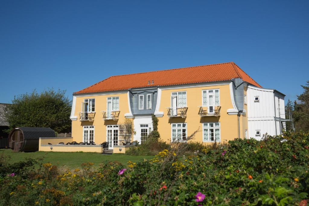 une maison jaune avec un toit rouge dans l'établissement Hjorths Badehotel, à Kandestederne