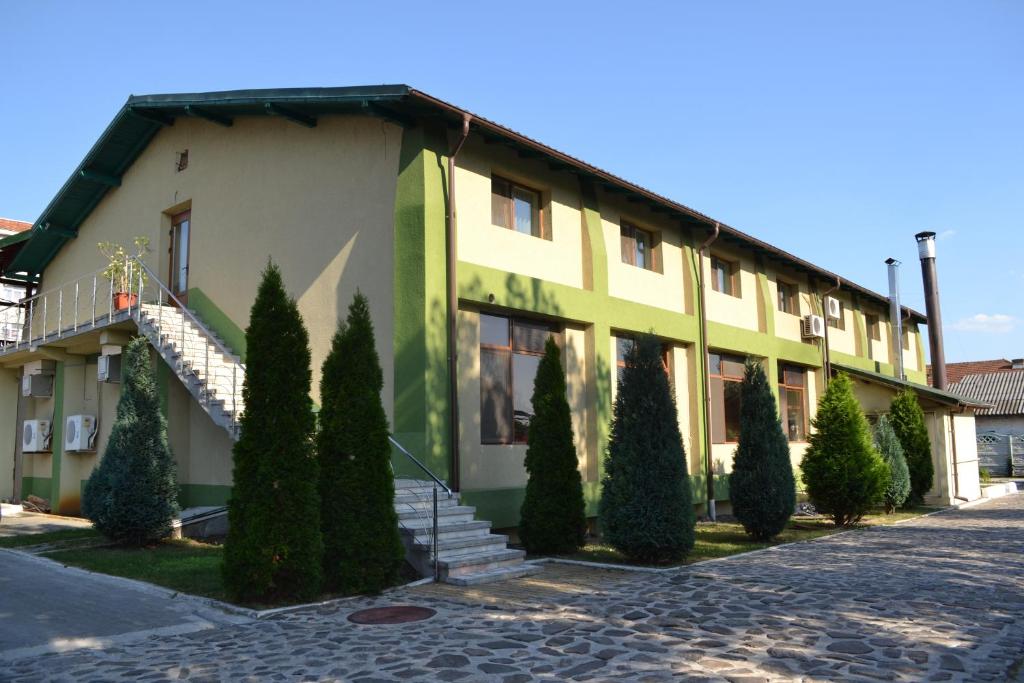 a building with trees and stairs in front of it at Motel Mesterul Manole in Curtea de Argeş