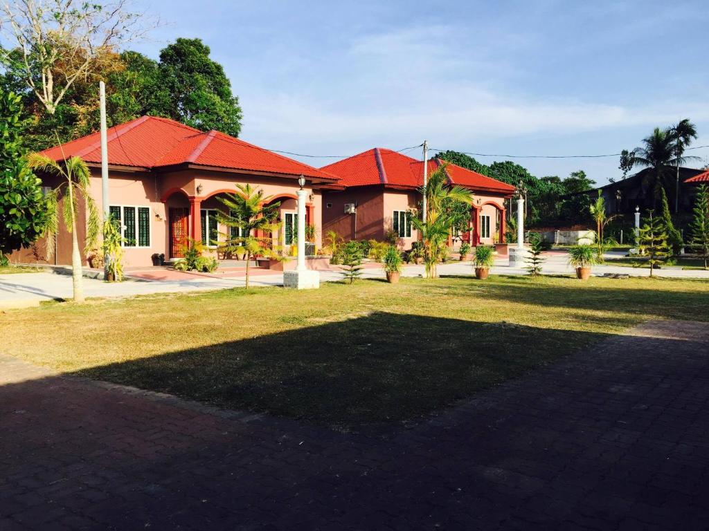 een huis met een rood dak en een tuin bij Harmony Guesthouse Sdn Bhd in Kampung Padang Masirat