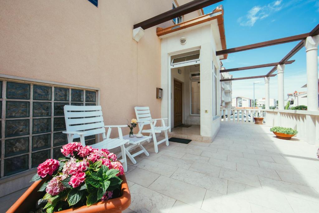 un patio con sillas blancas y flores en un edificio en Guesthouse Ante, en Split
