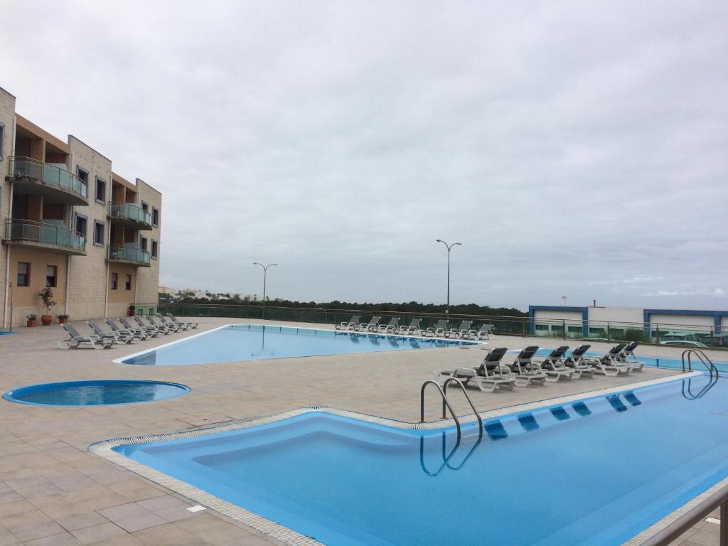 a large swimming pool with chairs and a hotel at Ericeira Surf and Sun in Ericeira
