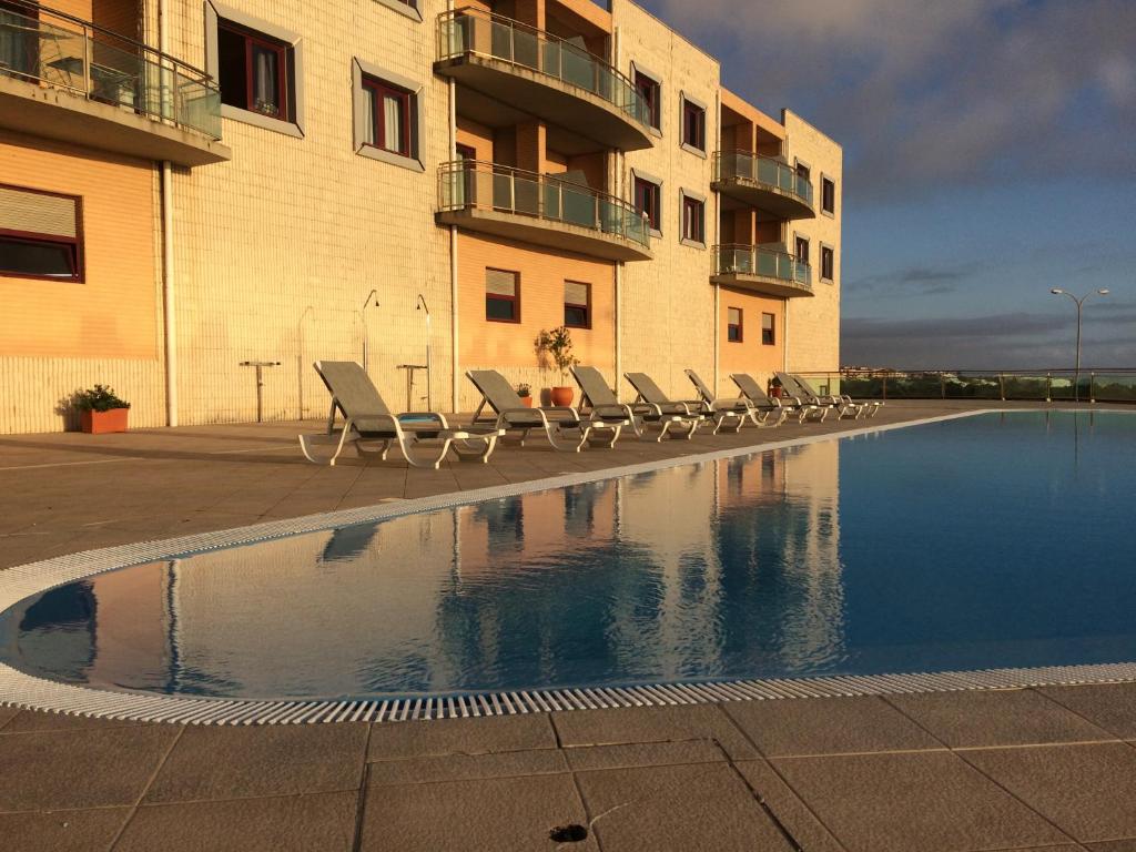 a swimming pool with lounge chairs next to a building at Ericeira Surf and Sun in Ericeira