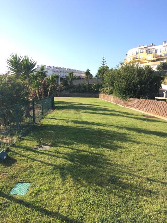 a large grassy yard with a fence and palm trees at Ericeira Surf and Sun in Ericeira
