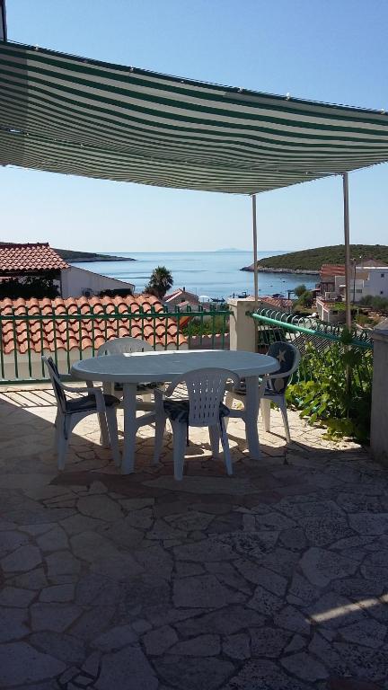 a white picnic table and two chairs under an umbrella at Apartments Miriam Karol in Rukavac