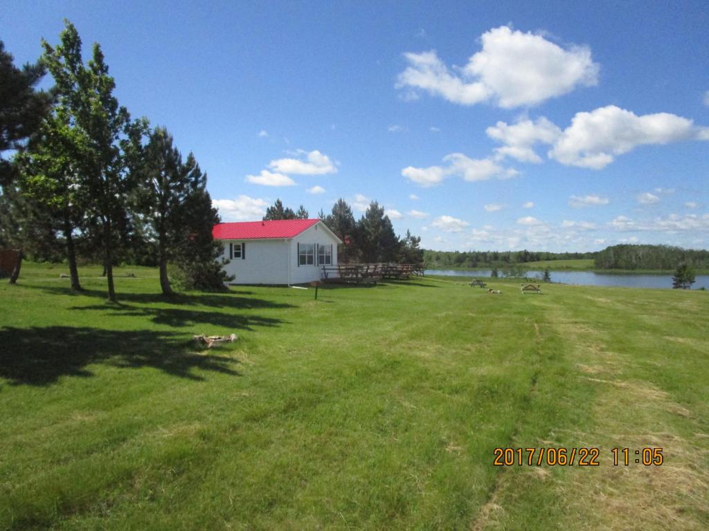 a large grass field with a white house and a lake at Sea'scape Cottages in Bayfield
