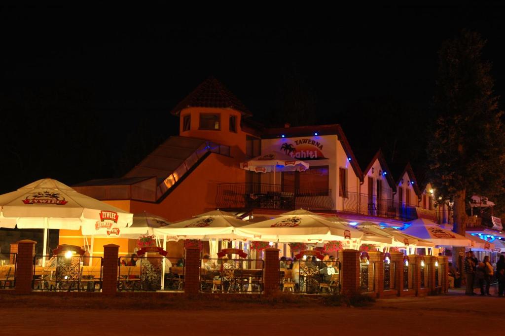 un edificio con mesas y sombrillas por la noche en Pensjonat Tahiti, en Rowy