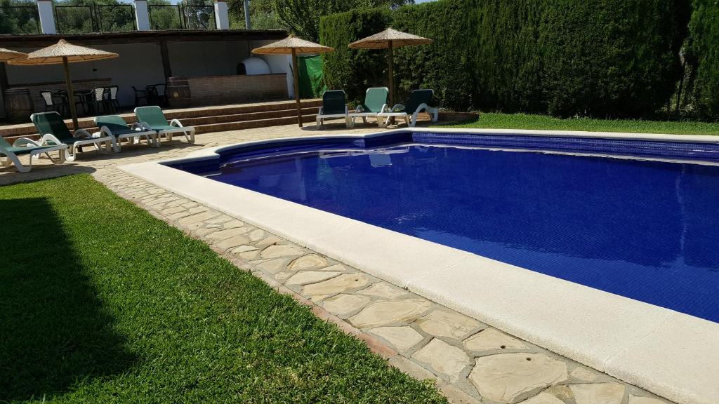 una piscina en un patio con sillas y sombrillas en La Posada del Duende, en Arcos de la Frontera