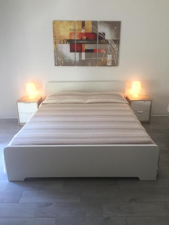 1 cama blanca en una habitación con 2 lámparas en happy holidays en Noto