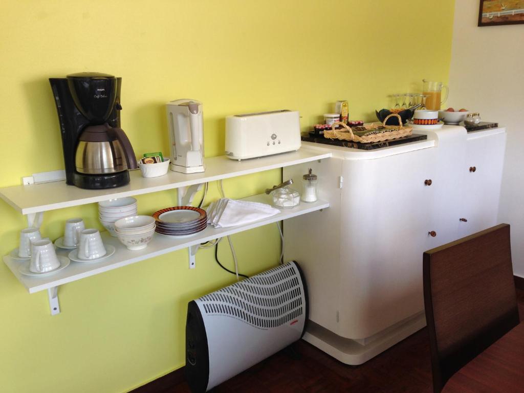 a kitchen with white shelves on a yellow wall at Domestival in Vila Verde dos Francos