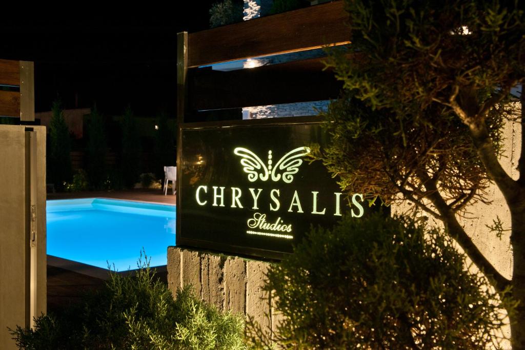 a sign next to a swimming pool at night at Chrysalis studios in Stavros