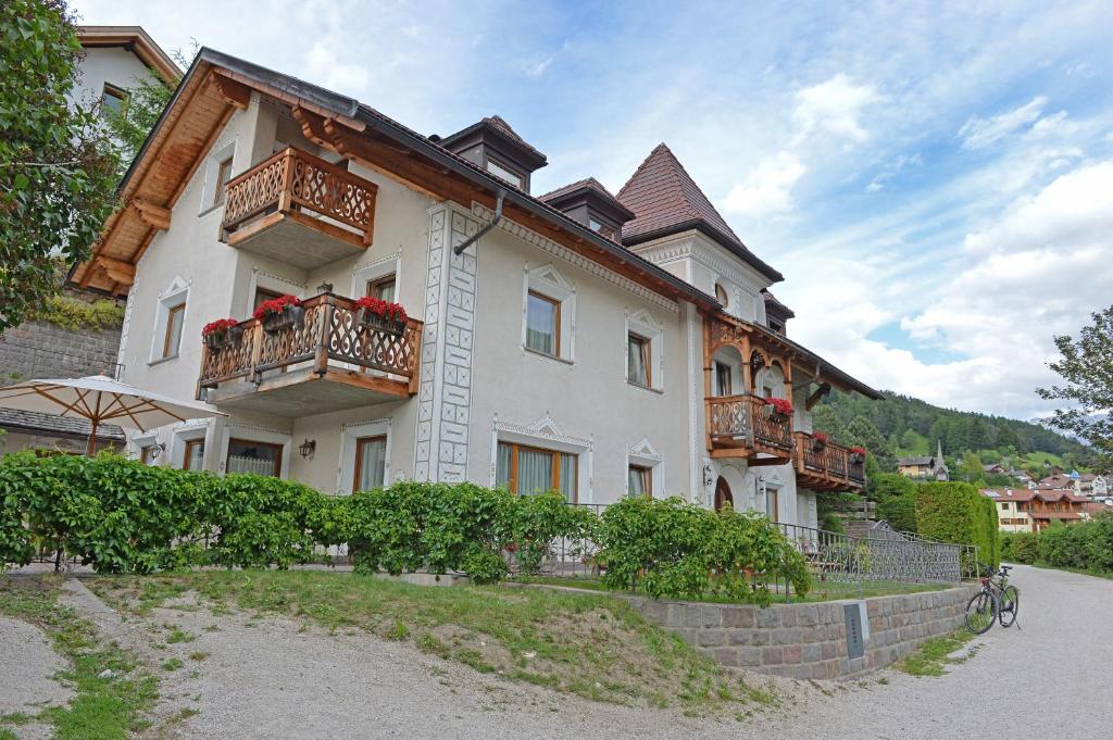ein großes weißes Gebäude mit Balkon auf der Seite in der Unterkunft Villa sulla passeggiata in St. Ulrich in Gröden