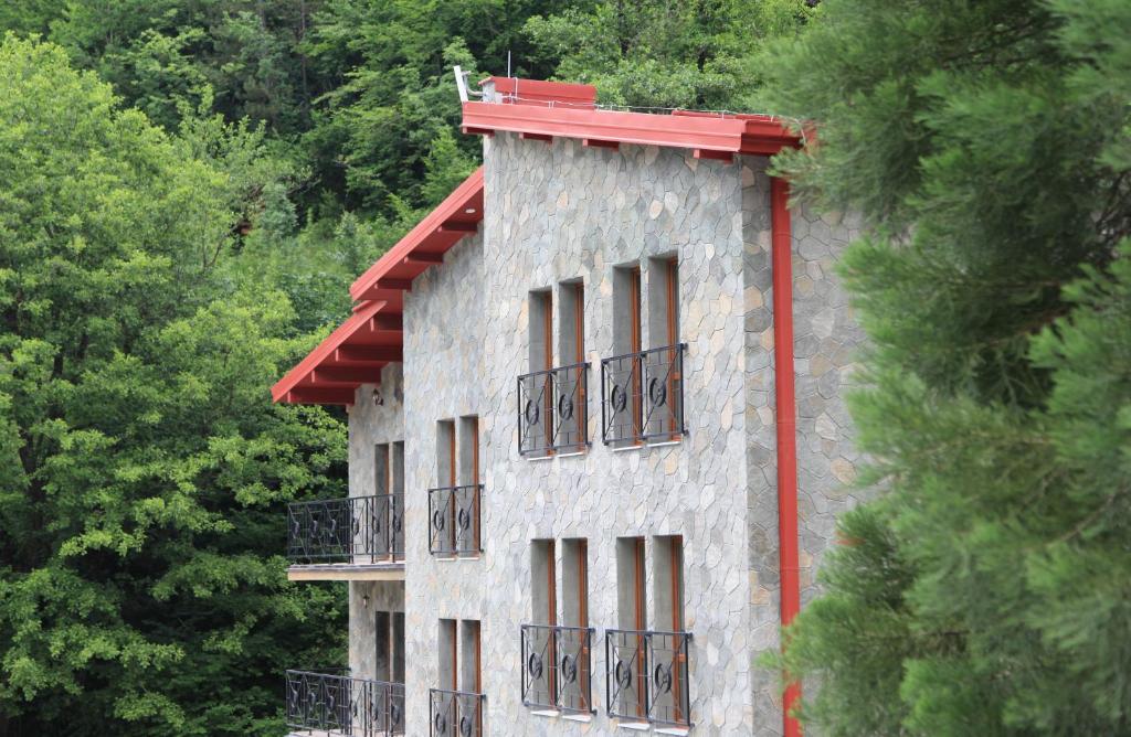Hotel Korab Trnica في Trnica: مبنى بسقف احمر ونوافذ واشجار
