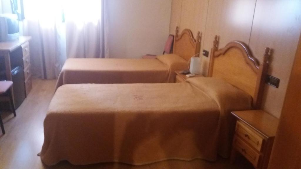 Duas camas num pequeno quarto com uma mesa em Hostal Bonaterra em Maçanet de la Selva