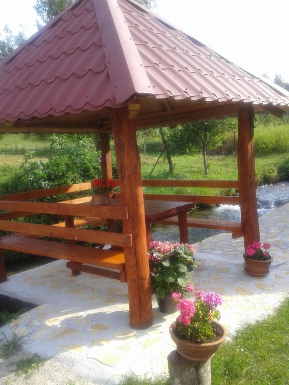 una mesa de picnic de madera con techo rojo en Guest House Mila, en Plitvički Ljeskovac
