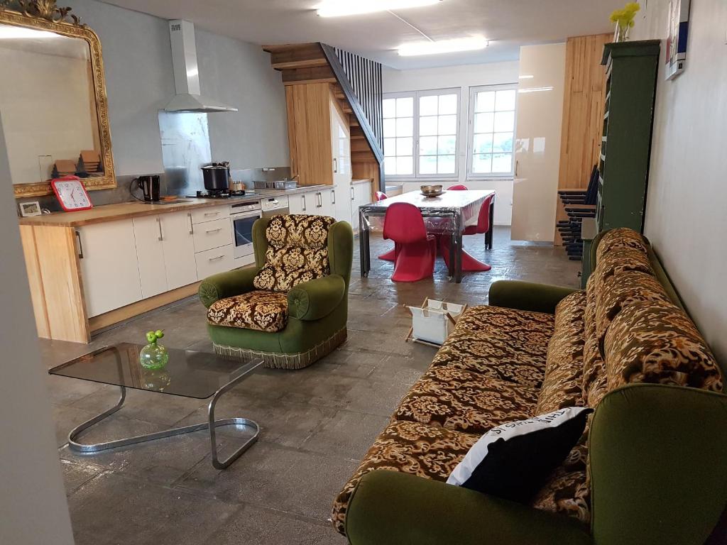 uma sala de estar com um sofá, cadeiras e uma mesa em L'Atelier du Tailleur à 5 mn du Puy du Fou em Chambretaud