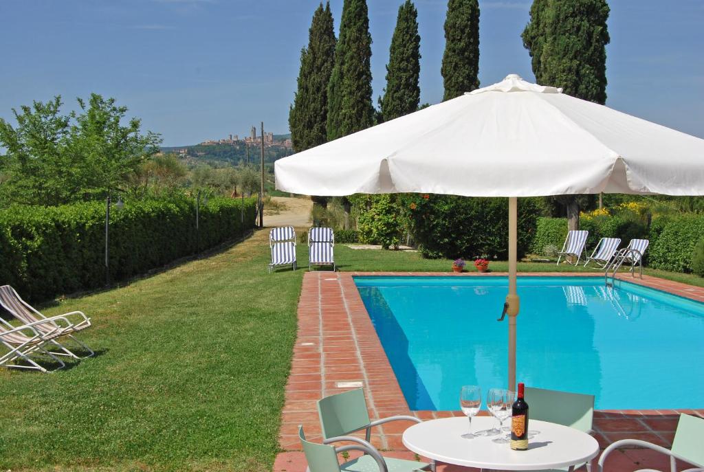 a table with an umbrella next to a swimming pool at Podere Remignoli in San Gimignano