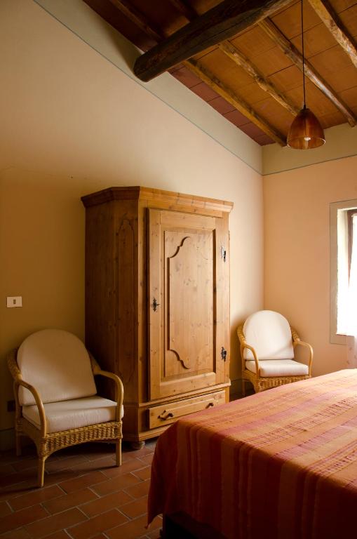 a bedroom with two chairs and a cabinet and a bed at Podere Remignoli in San Gimignano
