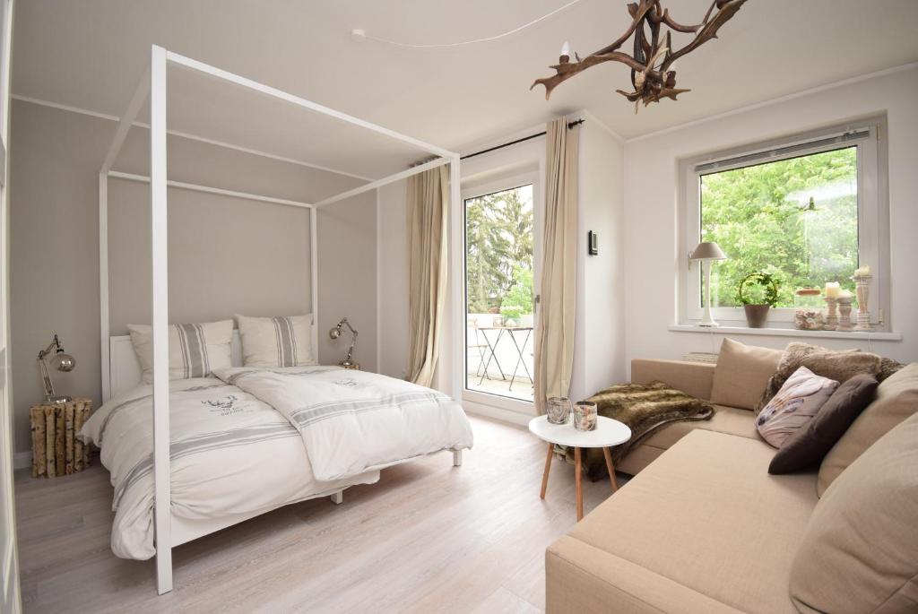 ein weißes Schlafzimmer mit einem Bett und einem Sofa in der Unterkunft Ferienwohnung Zweisamkeit in Bad Harzburg
