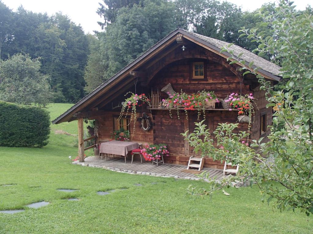 una cabaña de madera con una mesa y flores. en Le Grenier, en Saint-Paul-en-Chablais