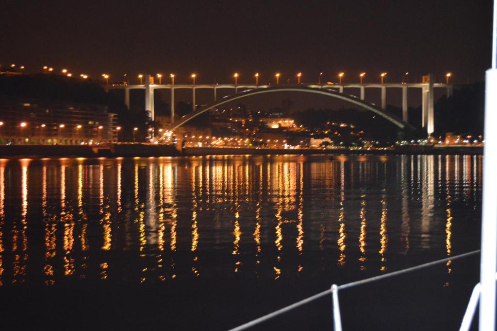Noite a bordo c/PA em veleiro -rio Douro في فيلا نوفا دي غايا: جسر فوق هيئة ماء في الليل