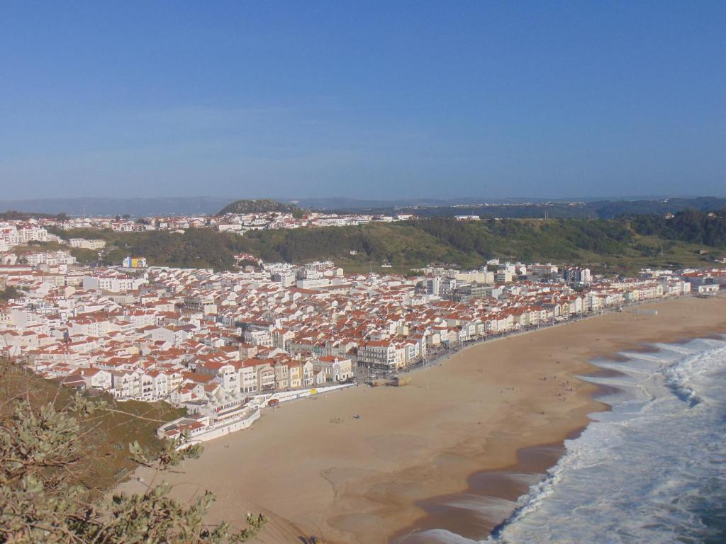 ナザレにあるVivenda Barrosoの建物と海を望むビーチの景色を望めます。