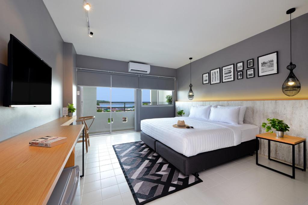 een slaapkamer met een bed, een bureau en een televisie bij Ruenthip Pattaya in Noord Pattaya