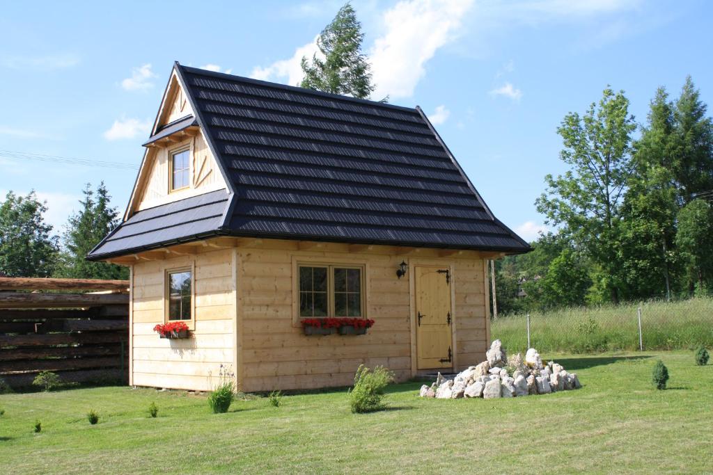 a small wooden house with a black roof at Chatka pod Tatrami in Kościelisko