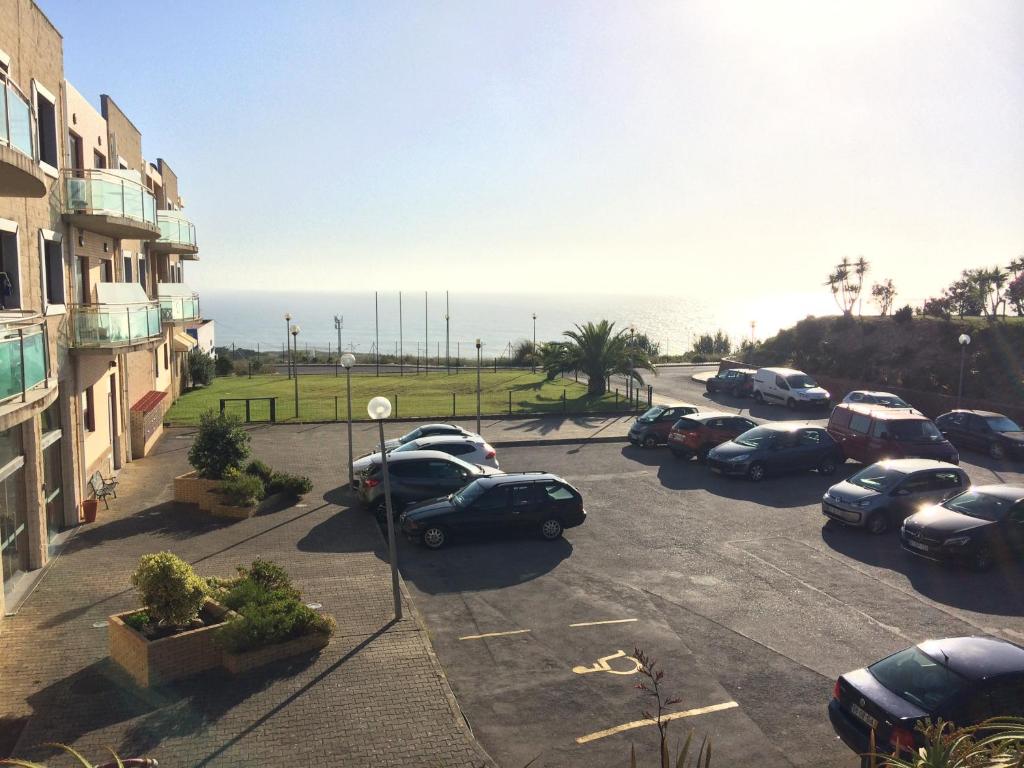 a parking lot with cars parked next to the ocean at Ericeira Surf and Sun in Ericeira