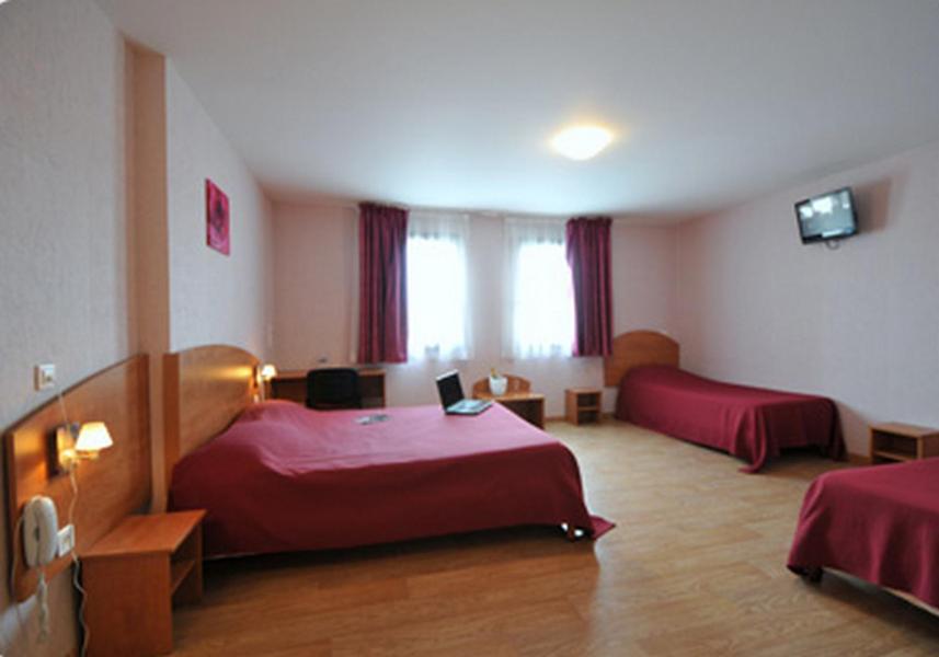 Witry-lès-Reimsにあるプリム ホテル ランスのベッド2台とテレビが備わるホテルルームです。