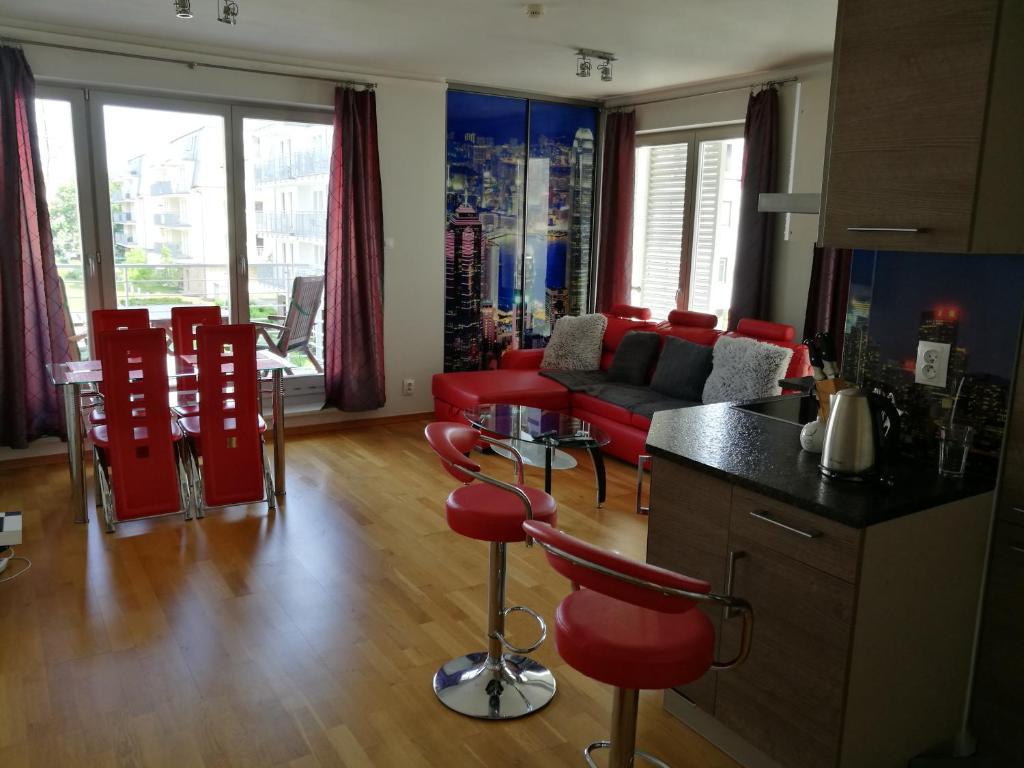 a kitchen and living room with red chairs and a table at Apartament Świnoujście Casa Marina SPA in Świnoujście