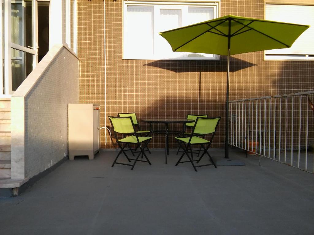 リスボンにあるZen Newton Apartmentのパティオ(テーブル、椅子、緑のパラソル付)