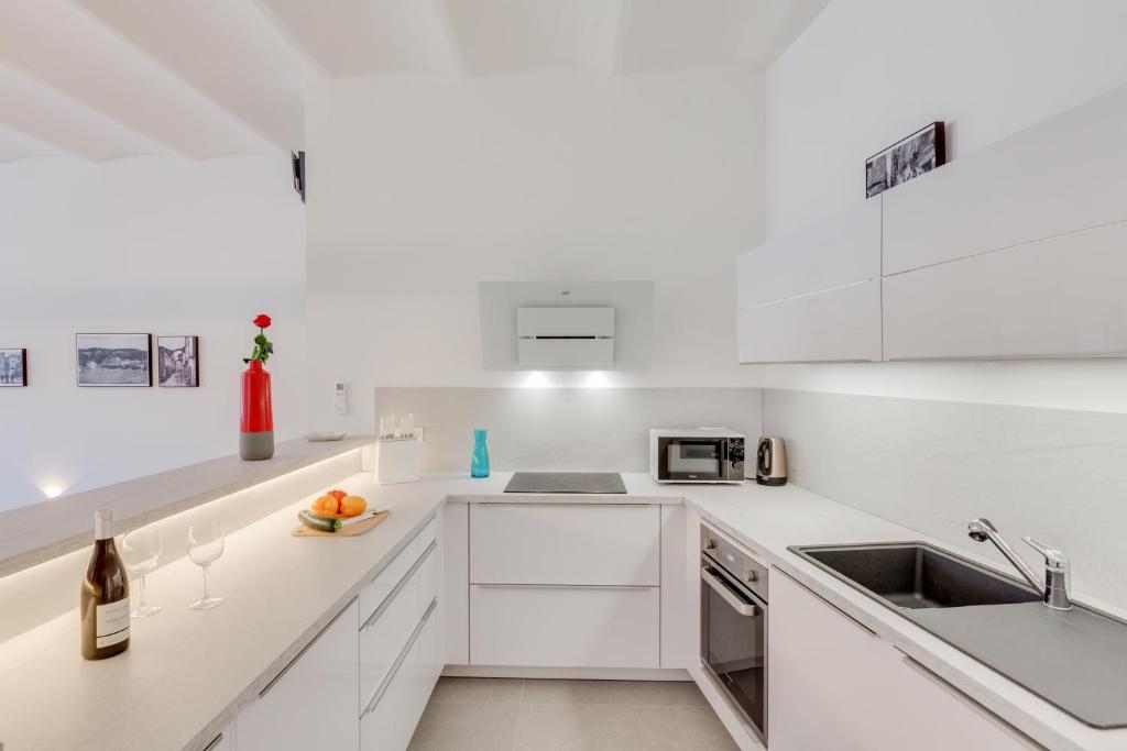 a white kitchen with white cabinets and a sink at Les Appartements du Port in Bonifacio