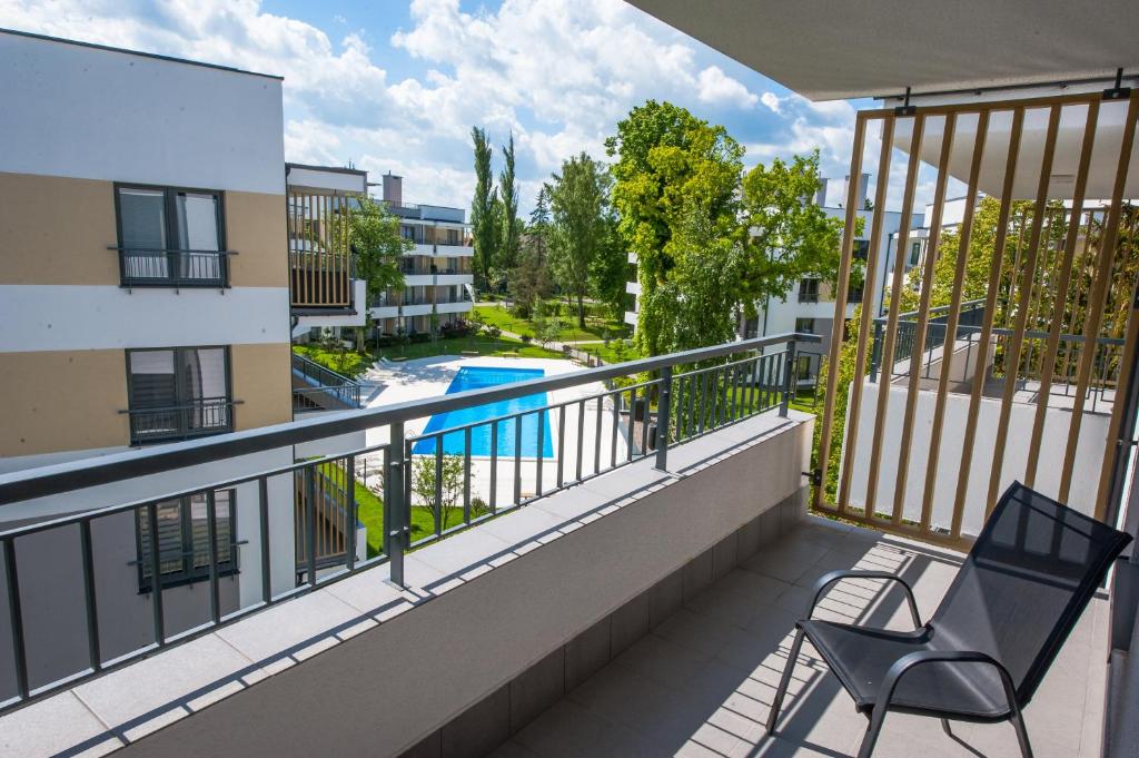 balcón con silla y piscina en Apartamenty Sea Stars, en Ustronie Morskie