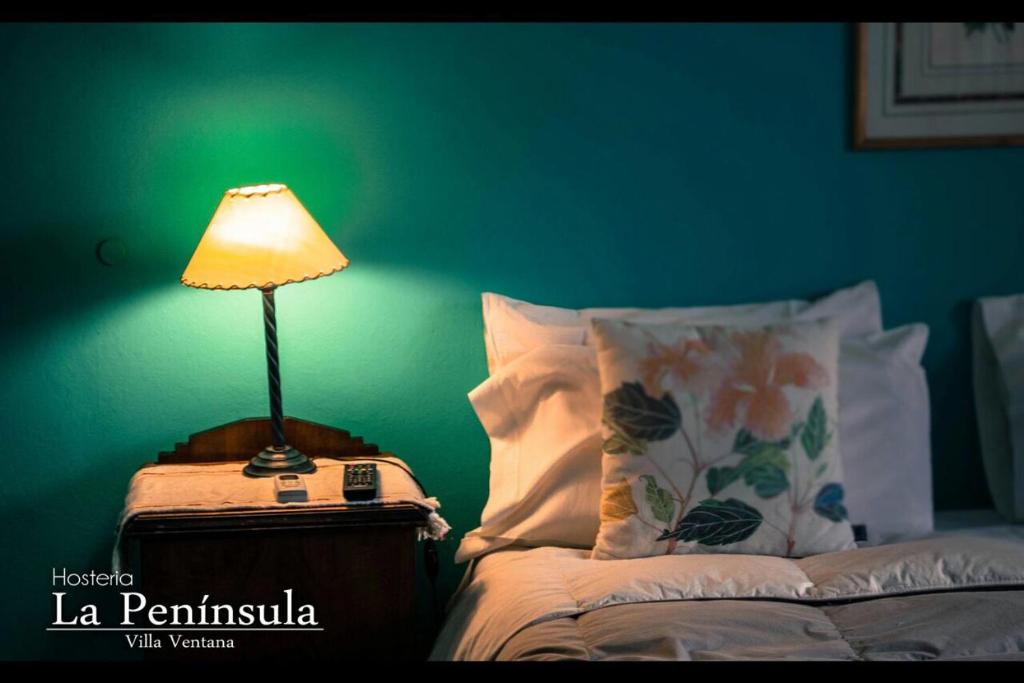 una lámpara sentada en una mesita de noche junto a una cama en Hostería La Península en Villa Ventana