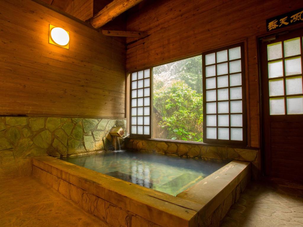 a jacuzzi tub in a room with windows at Oogi Onsen Oogiso in Minamioguni