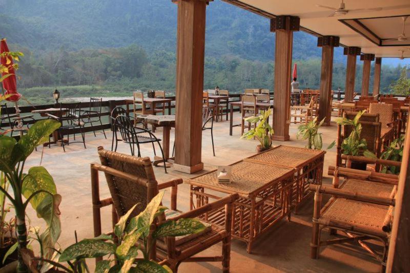 a patio with tables and chairs and a view of the mountains at Ning Ning Guesthouse in Muang Ngoy