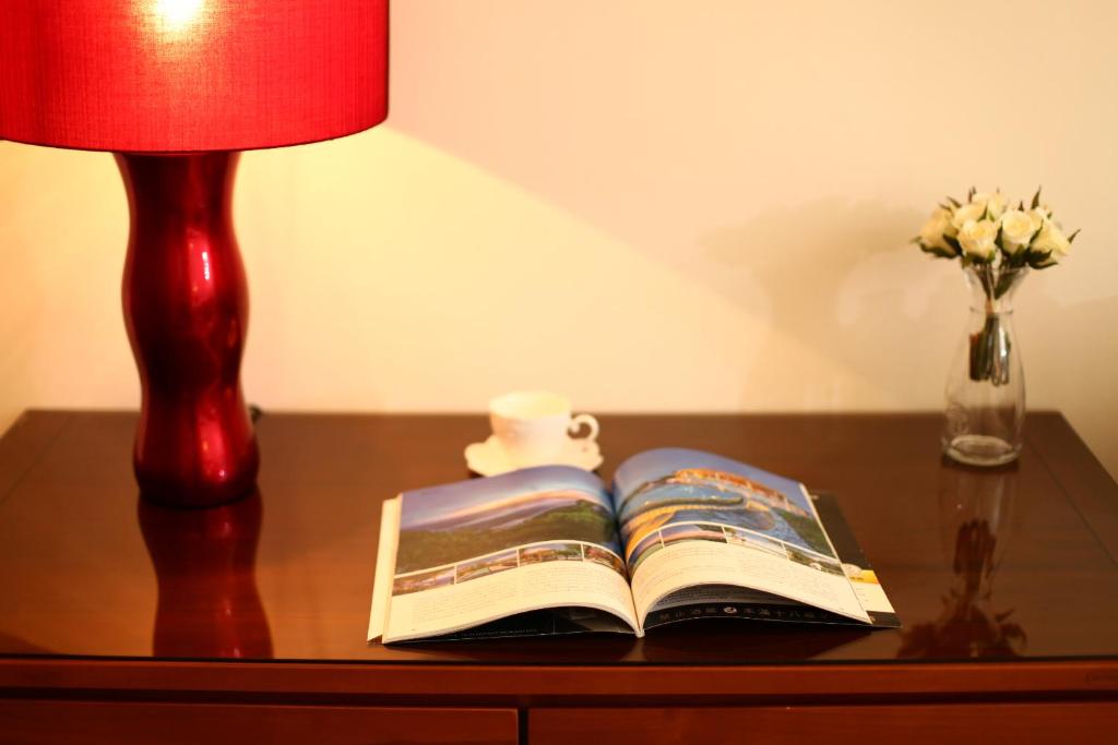 a book on a table with a lamp and a vase of flowers at When the Swallow Flying B&B in Taitung City